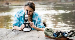 Girl outdoors looking through microscope
