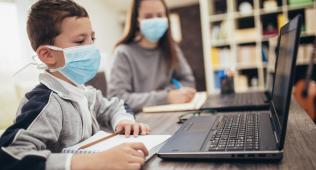 Boy and teacher with mask on laptops